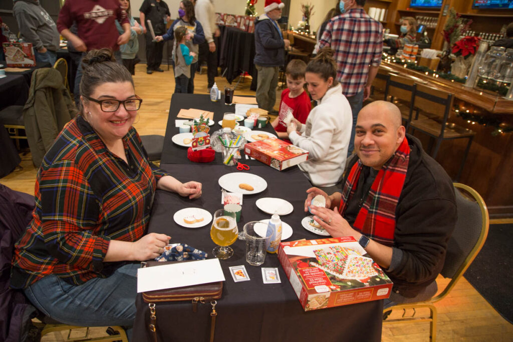 Couple having fun making a gingerbread house for Christmas at 49th State Brewing